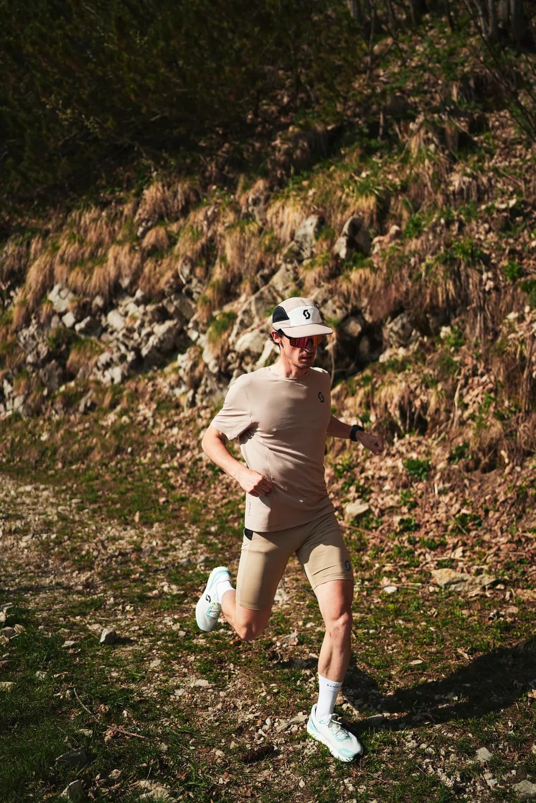 Thomas Derême courant en montagne, casquette blanche et tenue de trail